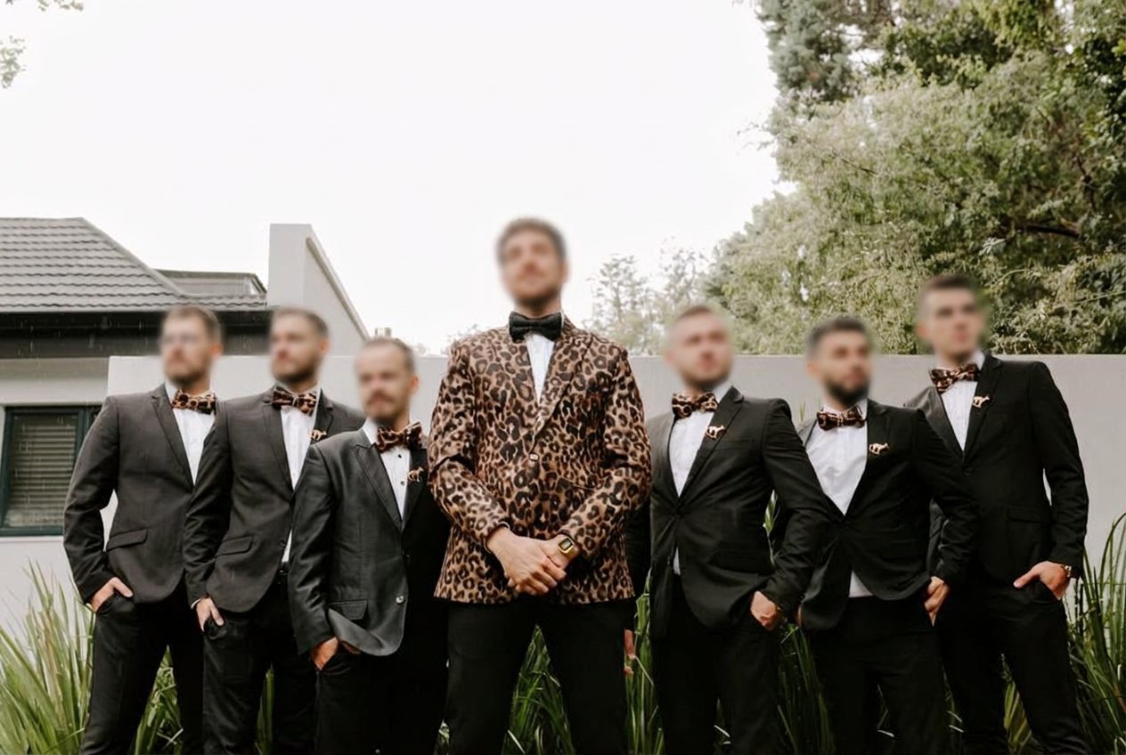Groom in a custom leopard-print tuxedo with his groomsmen in black suits, all tailored by Jet Smart Tailor