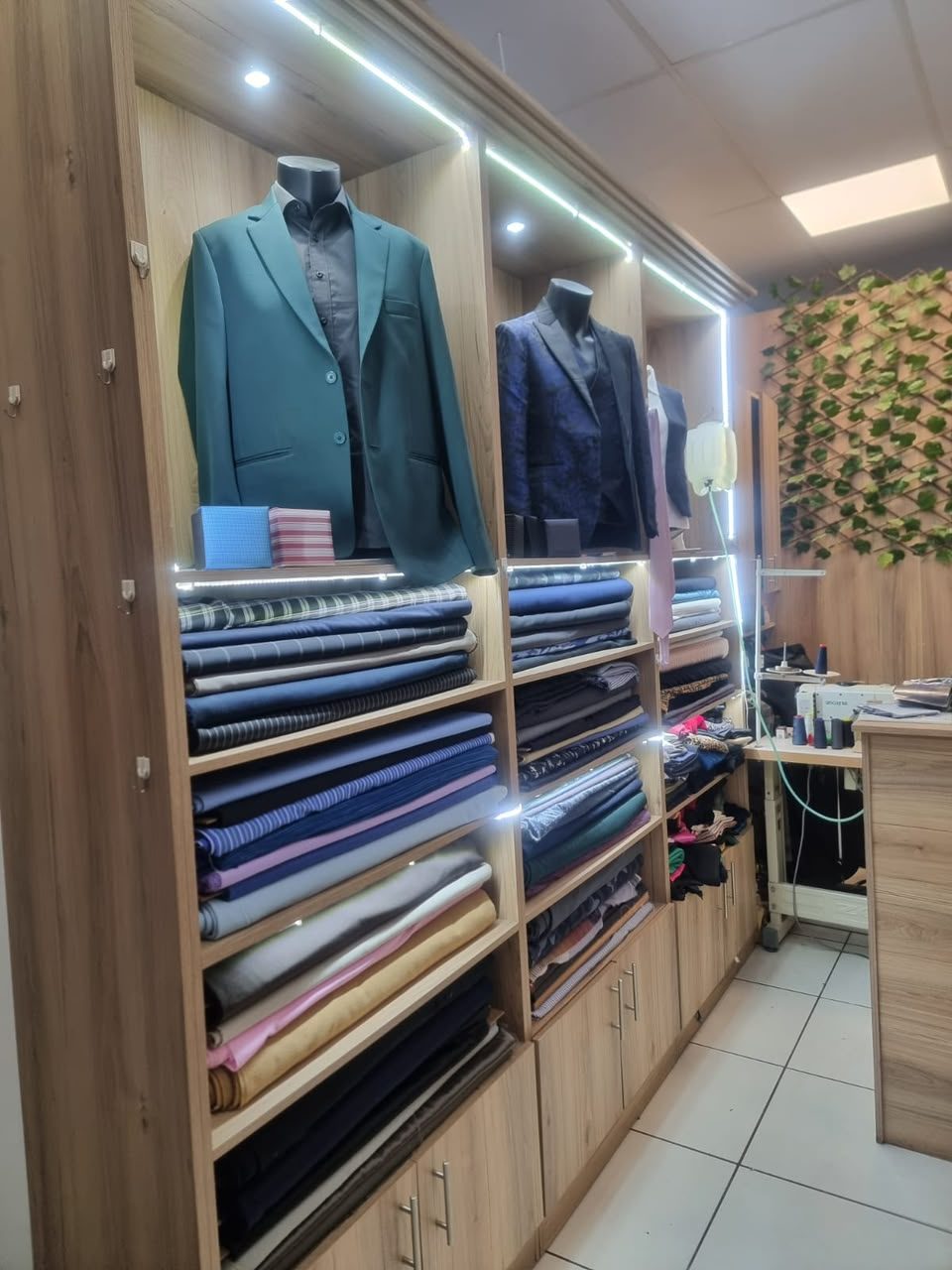 Jet Smart Tailor showroom display of handmade jackets above shelves of premium fabrics